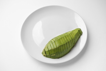 Sliced half avocado on a plate on white background with copy space. Close-up, top view