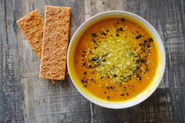 Pumpkin soup with bread on a wooden tabletop, top view