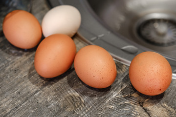 Chicken eggs lying on a wooden tabletop, top view, blurry background