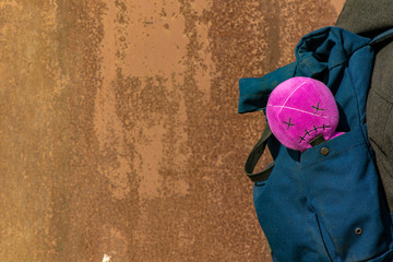 plush pink doll teenager hipster fashion style object in bag on rusty wall background texture empty...
