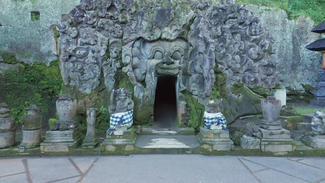Beautiful Reveal of the intricate stone carvings at the mouth of the hindu Goa Gajah Elephant Cave Temple in Ubud, Bali. An aerial of the ancient carvings of the sacred temple in exotic Indonesia 