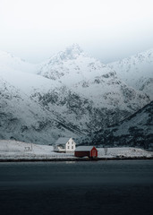 White house and a red cabin by the lake in wintertime