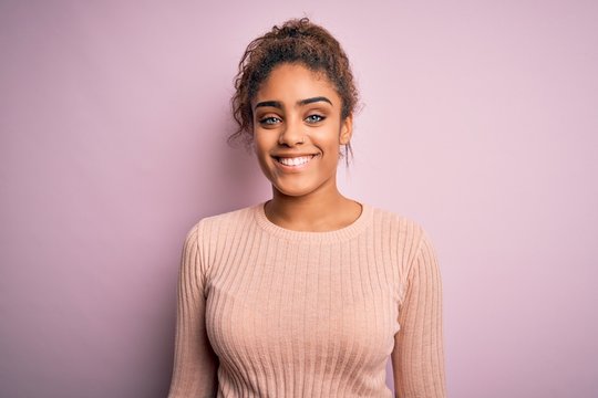Young beautiful african american girl wearing casual sweater standing over pink background with a happy and cool smile on face. Lucky person.