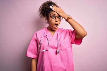 African american nurse girl wearing medical uniform and stethoscope over pink background surprised...