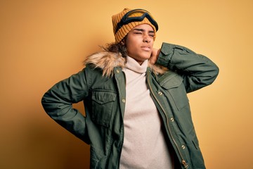 Young african american afro skier girl wearing snow sportswear and ski goggles Suffering of neck ache injury, touching neck with hand, muscular pain