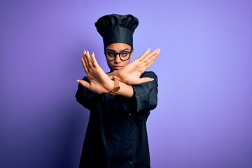 Young african american chef girl wearing cooker uniform and hat over purple background Rejection expression crossing arms and palms doing negative sign, angry face