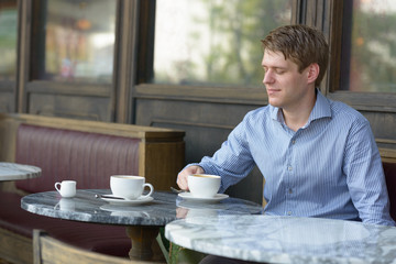 Fototapeta na wymiar Young blond businessman thinking at the coffee shop outdoors