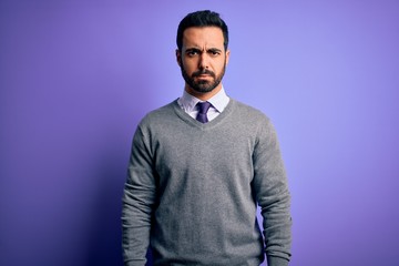 Handsome businessman with beard wearing casual tie standing over purple background skeptic and nervous, frowning upset because of problem. Negative person.