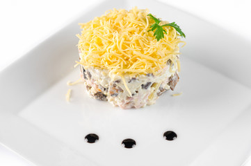 Calad round shape with grated cheese and sauce on a white square plate side view closeup