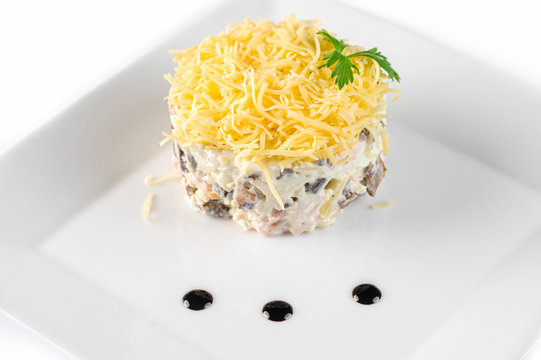 Calad round shape with grated cheese and sauce on a white square plate side view closeup