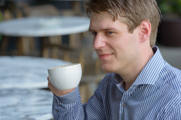 Face of young handsome blond businessman at the coffee shop outdoors