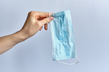 A hand holds a medical protective mask on a white background.