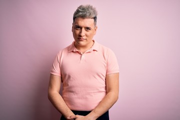 Young handsome modern man wearing casual pink t-shirt over isolated background skeptic and nervous,...