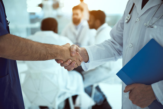 Male healthcare workers shaking hands in clinic