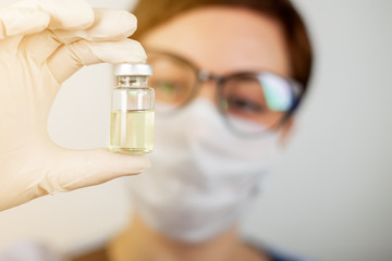 A doctor or nurse in nitrile gloves holds in his hand a vaccine vaccinated against influenza,...