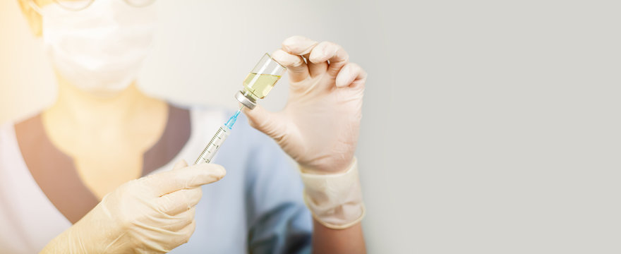 Hand Of A Doctor Or Nurse In Nitrile Gloves With A Syringe Needle Vaccinated Against Influenza, Measles, Coronavirus COVID-19