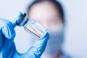Fototapeta premium woman doctor or scientist wearing face mask protective in lab holding medicine liquid vaccines