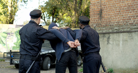 Two Police Officer Arresting Young Man. Police enforcement concept.
