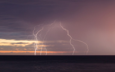 Lightning storm over the ocean at sunset