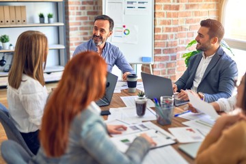 Group of business workers working together. Sitting on desk using laptop reading documents at the office