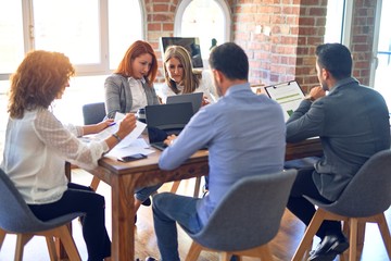 Group of business workers working together. Sitting on desk using laptop reading documents at the office