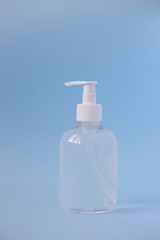 Bottle of alcohol transparent sanitizer for hands on blue background, vertical orientation. Coronavirus protection