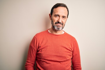 Fototapeta premium Middle age hoary man wearing casual orange sweater standing over isolated white background looking sleepy and tired, exhausted for fatigue and hangover, lazy eyes in the morning.