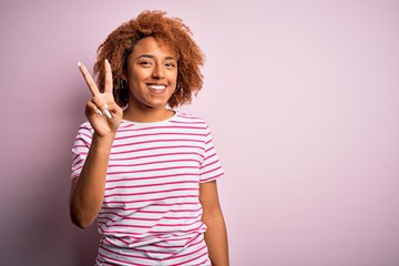 Young beautiful African American afro woman with curly hair wearing casual striped t-shirt showing and pointing up with fingers number two while smiling confident and happy.