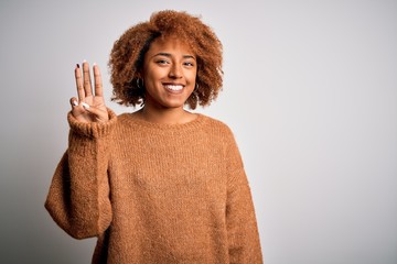 Young beautiful African American afro woman with curly hair wearing casual sweater showing and...