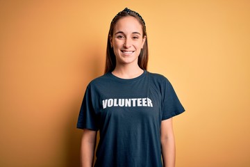 Young beautiful woman wearing volunteer t-shirt doing volunteering over yellow background with a...