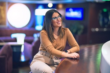 Young beautiful woman smiling happy and confident. Sitting with smile on face leaning on the counter bar at restauran