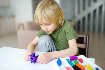 Little boy playing dough at home during coronavirus quarantine. Child is molding from plasticine model virus covid-19. Creativities lessons, homeschooling. Kids entertainments while stay home.
