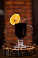 Mulled wine in a glass with an orange, wood backgroud