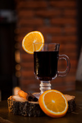 Mulled wine in a glass with an orange, wood backgroud