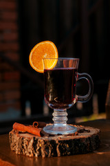 Mulled wine in a glass with an orange, wood backgroud