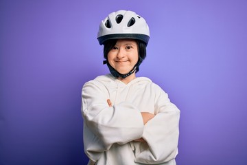 Young down syndrome cyclist woman wearing security bike helmet over purple background happy face smiling with crossed arms looking at the camera. Positive person.
