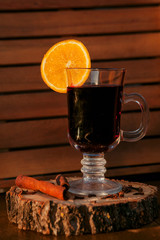 Mulled wine in a glass with an orange, wood backgroud
