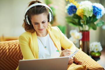 smiling learner woman with headphones watching internet lessons