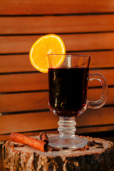 Mulled wine in a glass with an orange, wood backgroud