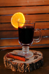 Mulled wine in a glass with an orange, wood backgroud