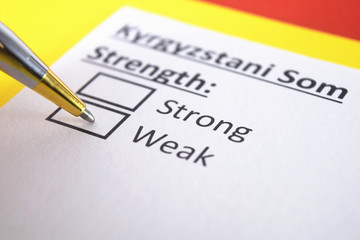 One person is answering question about strength of Kyrgyzstani Som.