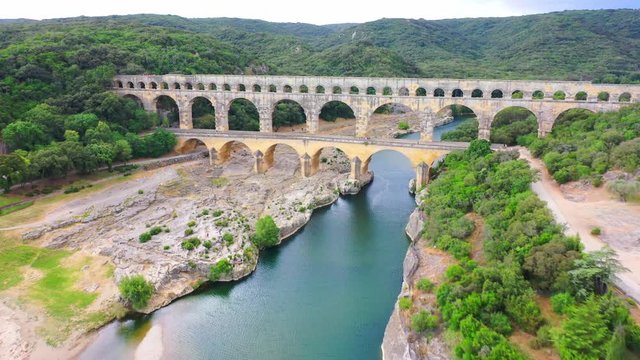 Low altitude aerial of Pont du Gard is an ancient Roman aqueduct that crosses the Gardon River near the town of Vers-Pont-du-Gard in southern France and popular tourist destination 4k