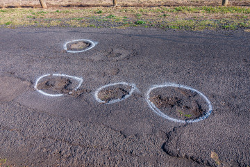 Broken road surface with white paint alert