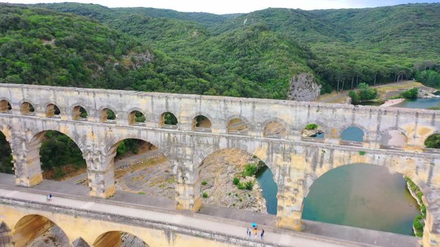 Low altitude aerial of Pont du Gard is an ancient Roman aqueduct that crosses the Gardon River near the town of Vers-Pont-du-Gard in southern France and popular tourist destination 4k