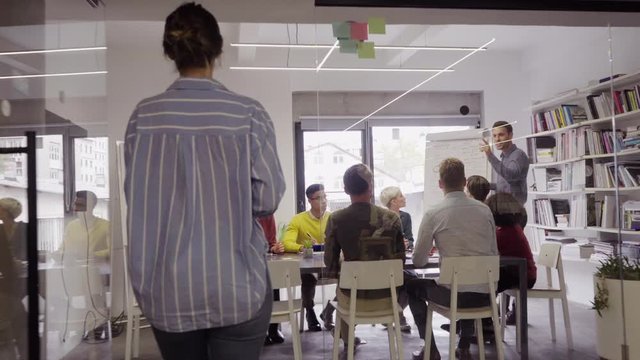 Confident mature businessman giving a presentation to his crative team in office. Business brief with annual goals with casual employees. Happy leadership man training businessmen and businesswomen.