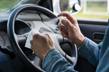 Man hands cleaning the steering wheel with a wipe and sanitizer. Covid-19 or Corona virus concept