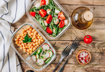 Healthy meal prep containers with chickpeas and spring salad with cucumbers, radish and chives and containers with caprese salad with arugula. Healthy lunch in glass containers. Zero waste concept.