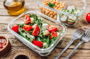 Healthy meal prep containers with chickpeas and spring salad with cucumbers, radish and chives and containers with caprese salad with arugula. Healthy lunch in glass containers. Zero waste concept.