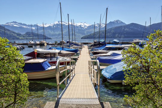 Boat harbour on the lake Lucerne overlooking the snow-capped Alps. Canton of Lucerne, Switzerland.