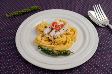 Stir-fried spaghetti and pork, beautifully arranged in a white plate.